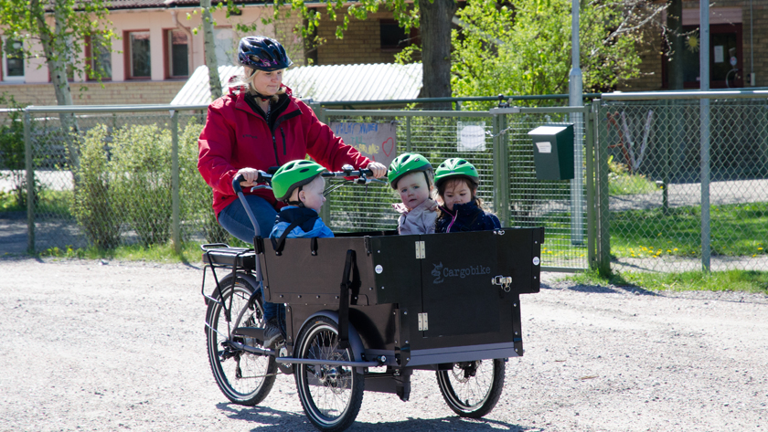 Två bilder i en och samma: Blå förskolebuss och förskolecykel, en cykel med stor låda  med barn i